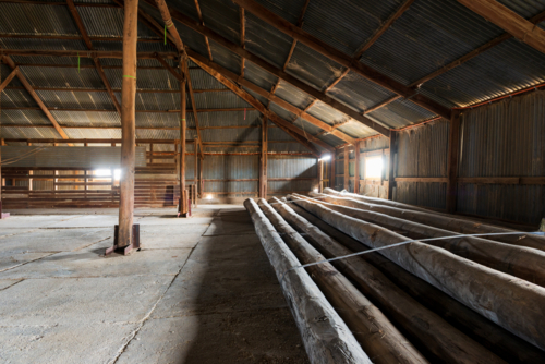 Interior of timber-framed shed with large wooden logs and corrugated walls. - Australian Stock Image