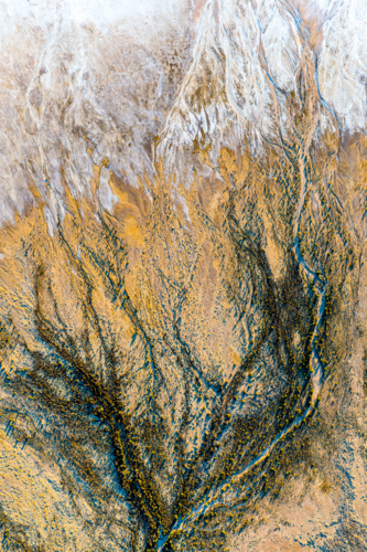 Intricate dark blue and golden erosion channels spread like veins across a textured salt pan - Australian Stock Image