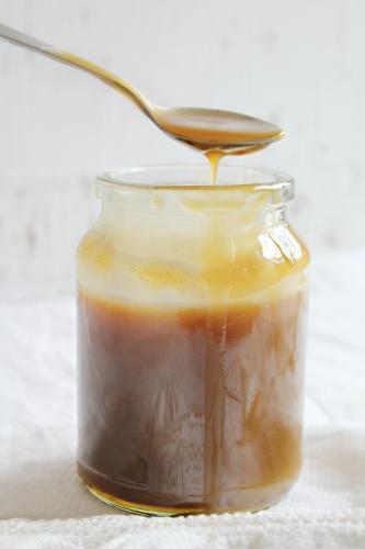 Jar of caramel sauce with spoon dripping