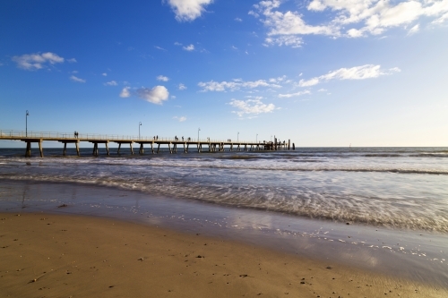 Jetty in late afternoon with waves lapping shore - Australian Stock Image