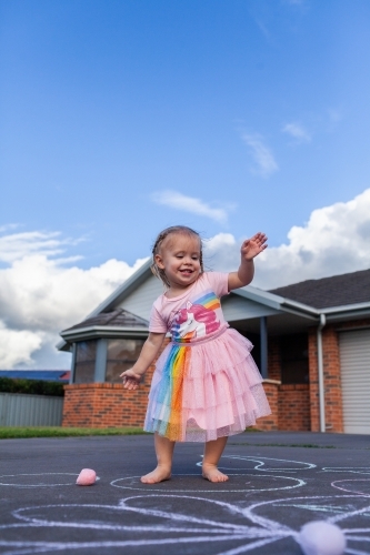 Joyful little girl in sparkly dress dancing outside home - Australian Stock Image