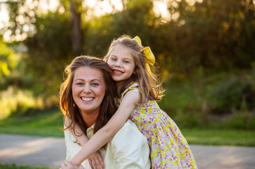 Joyful portrait of happy smiling mother and young daughter in golden light outdoors - Australian Stock Image