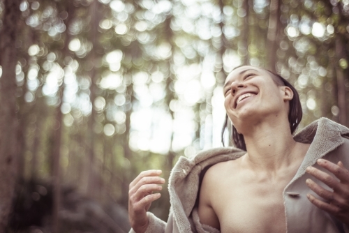 Joyful woman with jacket open laughing and dancing in the bush - Australian Stock Image