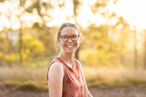 Joyful young person laughing in golden light outside - Australian Stock Image