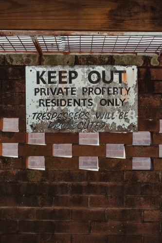 Keep out, private property sign on an old brick wall in a car port. - Australian Stock Image