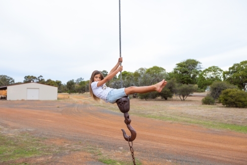Kid climbing on old crane hook cable - Australian Stock Image