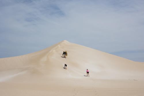 Kids climbing to top of sand dune in remote Australia - Australian Stock Image
