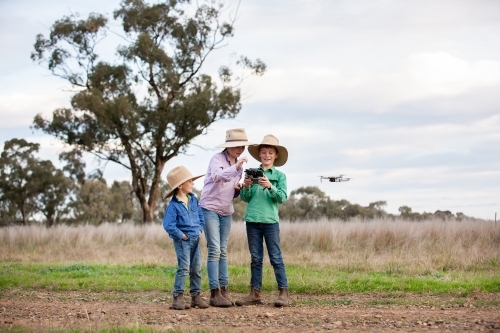 Kids flying a drone in a farm paddock