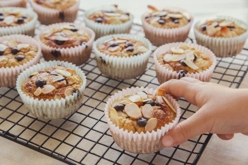 Kids hand picking up baked oatmeal cupcake - Australian Stock Image