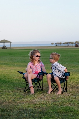 Kids having fun in camping chairs on the grass - Australian Stock Image