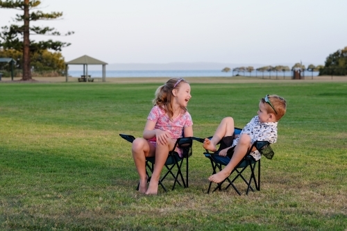 Kids having fun in camping chairs on the grass - Australian Stock Image