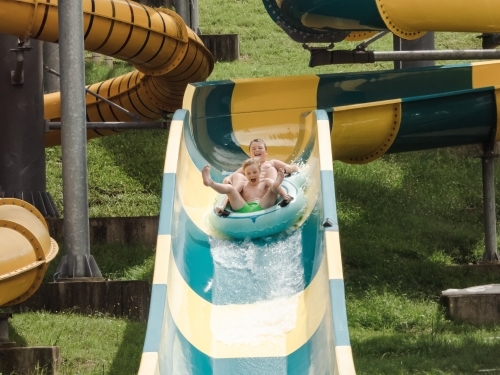 Kids having fun riding waterslide on summer holiday in Coffs Harbour, Australia - Australian Stock Image