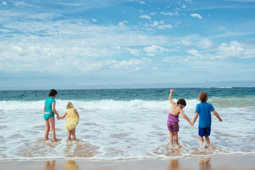 Kids holding hands in surf - Australian Stock Image