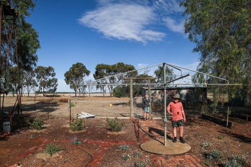 Kids in rural dry backyard in summertime with hills hoist washing line