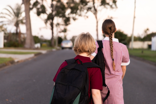 kids in uniform and with backpacks walking home after school - Australian Stock Image