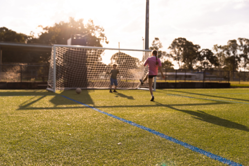 kids playing soccer with a goalie and striker - Australian Stock Image