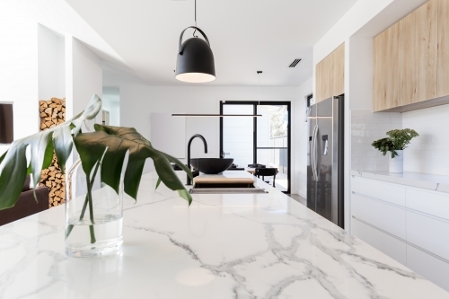 Kitchen marble bench close up with black hanging pendant and vase - Australian Stock Image