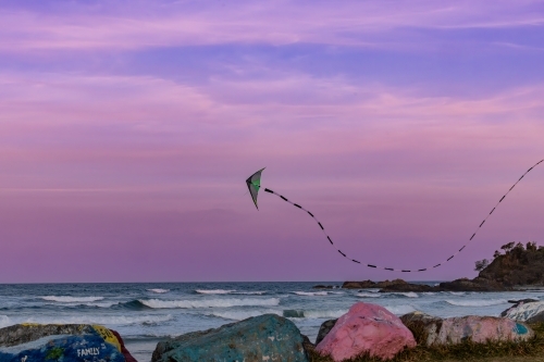 Kite flying over the Port Macquarie breakwall at sunset in pink sky - Australian Stock Image