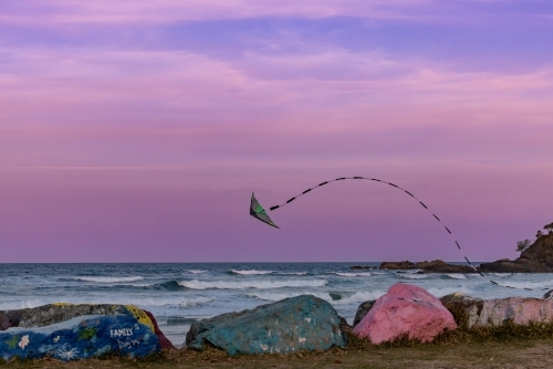 Kite flying over the Port Macquarie breakwall at sunset in pink sky - Australian Stock Image