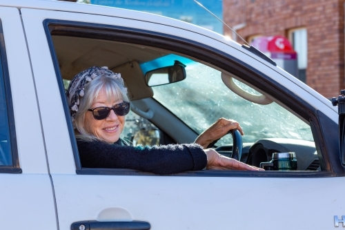 lady wearing sunglasses looking out of car window while driving