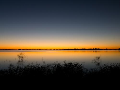 Lake with a sunset glow reflected along the horizon - Australian Stock Image