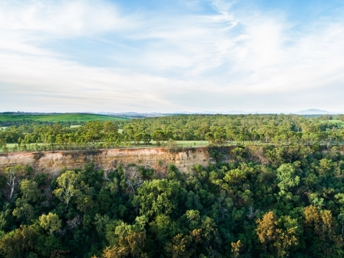 Landscape of cliff beside paddock and gum trees - Australian Stock Image