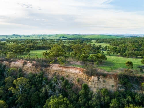 Landscape of cliff beside paddock and gum trees - Australian Stock Image