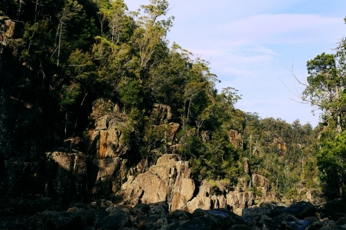 Landscape of rock face with trees in bushland - Australian Stock Image