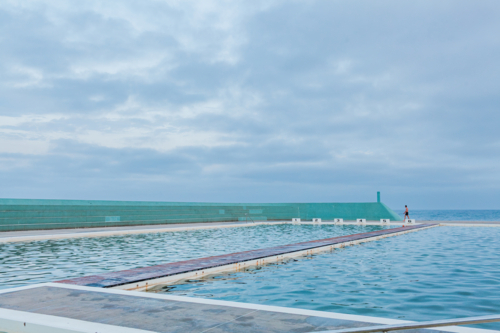 Landscape of the Newcastle Ocean Baths at dusk with blue overcast sky - Australian Stock Image