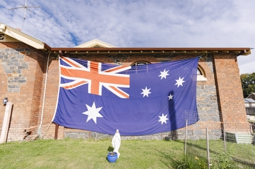 Large Australian flag flying on historic courthouse which in now a Police Station - Australian Stock Image