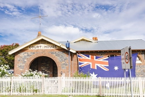 Large Australian flag flying on historic courthouse which is now a Police Station - Australian Stock Image