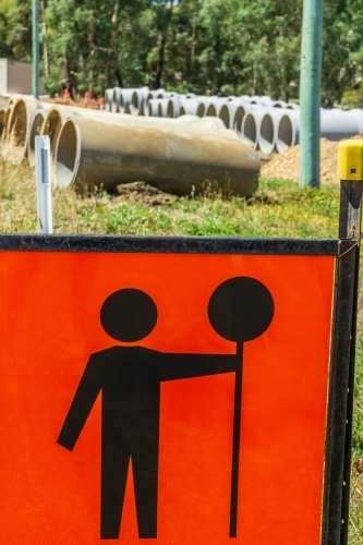 Large cement pipes laid out in rows behind a traffic sign - Australian Stock Image