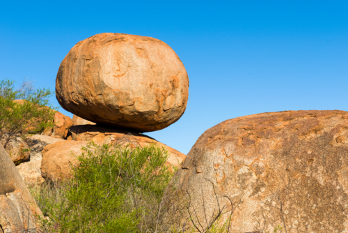 Large granite boulder balanced on another rock at Devils Marbles. - Australian Stock Image