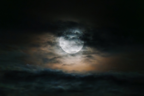 Large moon obscured in cloudy sky - Australian Stock Image