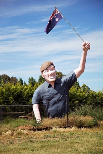 Large sculpture of man holding an Australian flag in a field
