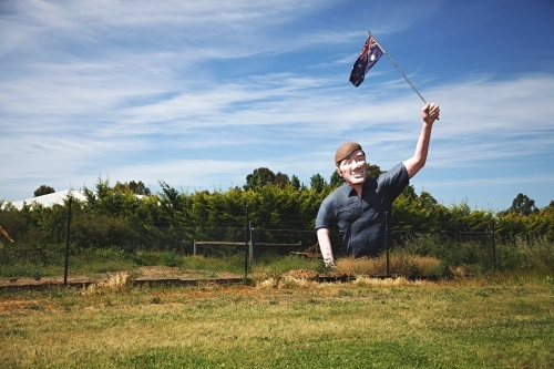 Large sculpture of man holding an Australian flag in a field - Australian Stock Image