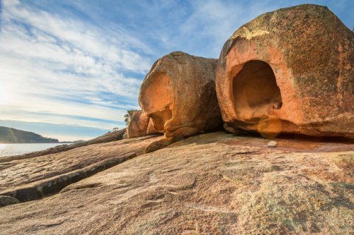 Large weathered rock formations covered in lichen, perched on a granite ledge - Australian Stock Image