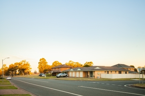 Last light on trees at intersection of quiet town street - Australian Stock Image