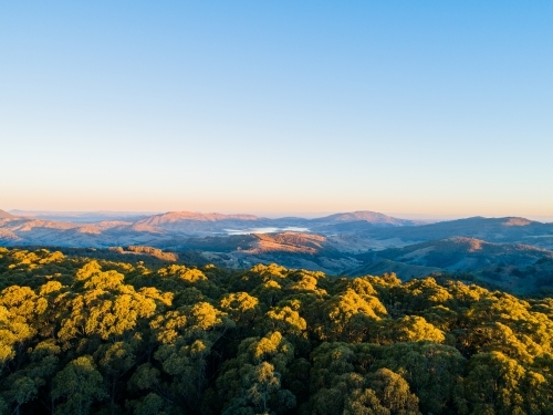Last sunset light touching the tops of mountains and trees - Australian Stock Image