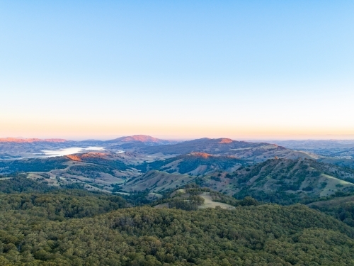 Last sunset light touching the tops of mountains and trees - Australian Stock Image