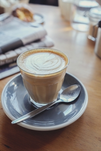 Latte coffee with newspaper on wooden table - Australian Stock Image