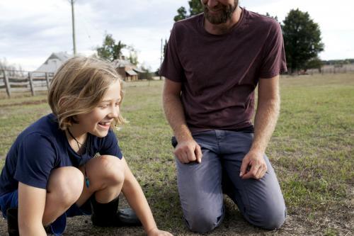 Laughing girl with father outside in paddock - Australian Stock Image