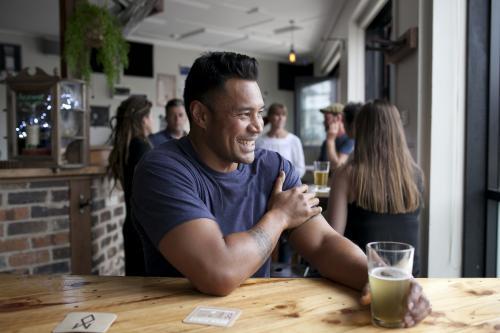 Laughing Polynesian man having a drink at local pub