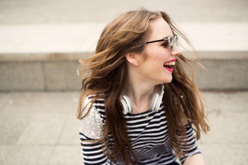 Laughing young woman looking over shoulder with headphones - Australian Stock Image