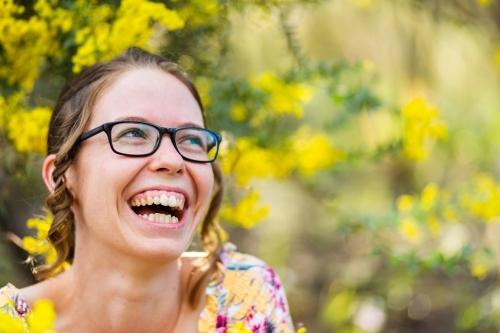 Laughing young woman with copy space and yellow blossoms - Australian Stock Image