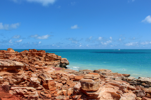 Layered red rocks along the waters edge - Australian Stock Image