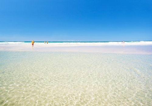 Leaving the beach into the clear ocean waters with the lifesaver in the distance - Australian Stock Image