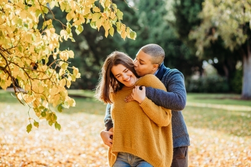 lgbtqi couple playing around and being silly outside near autumn trees - Australian Stock Image