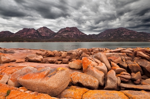 Lichen covered rocks and stormy sky at Coles Bay - Australian Stock Image