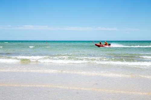 Lifesavers patrolling beach in rubber dinghy - Australian Stock Image